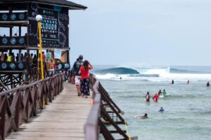 Pasarela de madera y olas de Cloud 9 en Siargao, Filipinas, con surfistas junto al arrecife