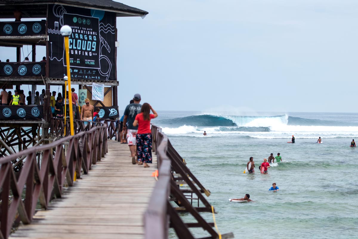 Pasarela de madera y olas de Cloud 9 en Siargao, Filipinas, con surfistas junto al arrecife