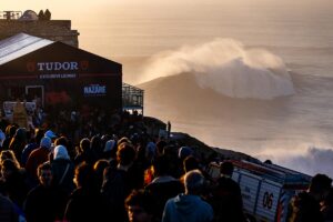 Público junto al fuerte de Nazaré mientras rompe una ola gigante en Praia do Norte.